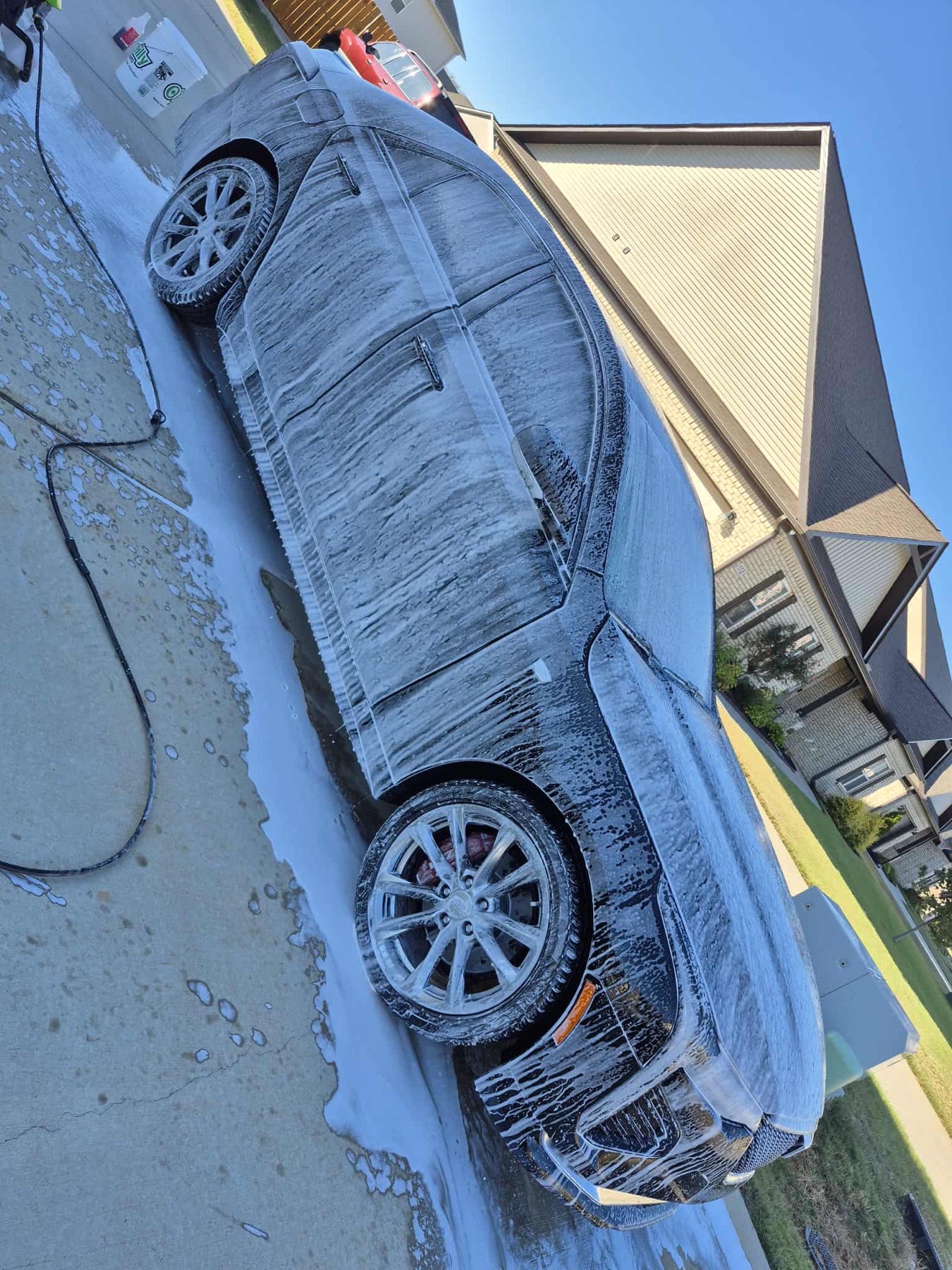 Black sedan covered in foam during wash process